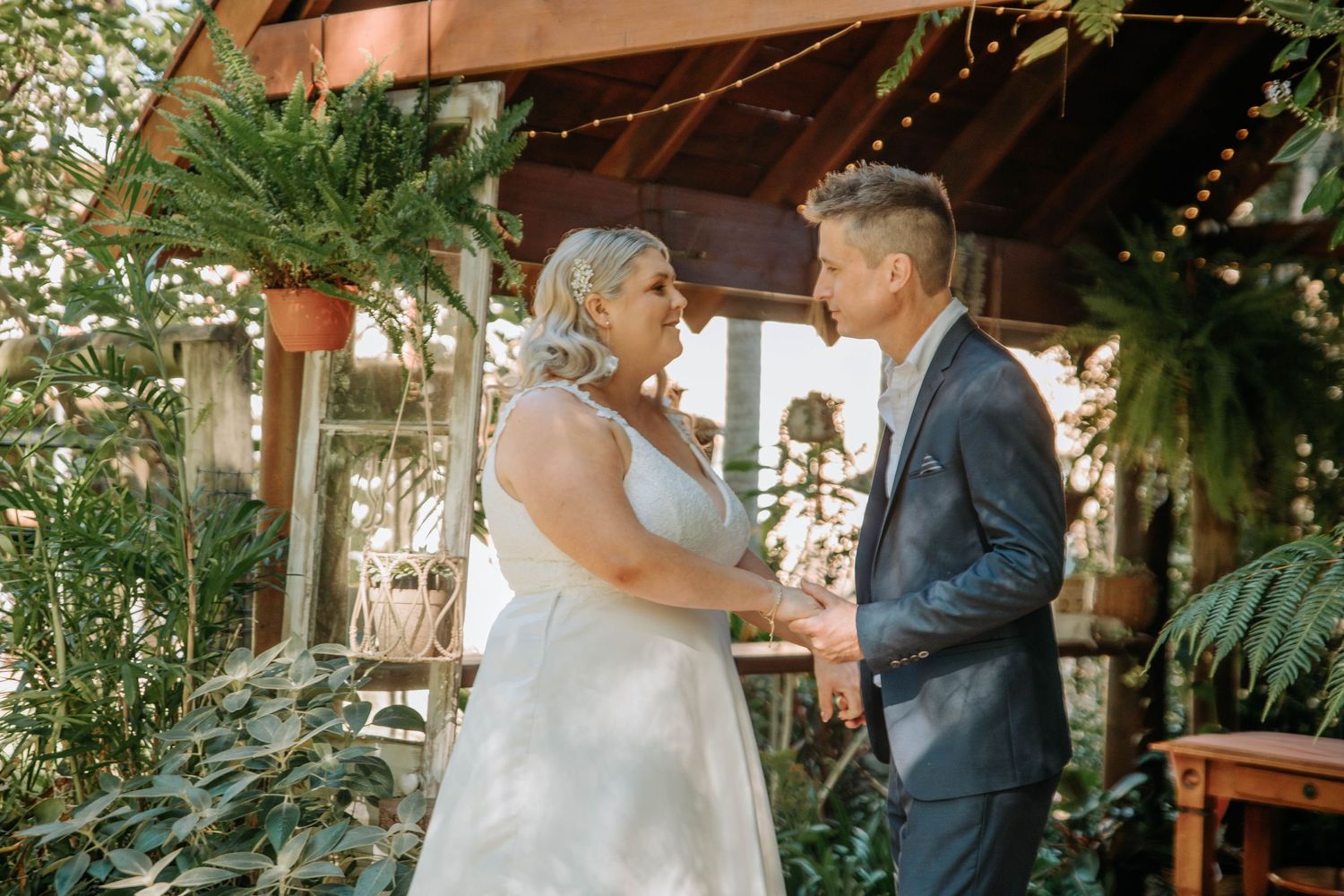 An intimate wedding moment shared under a covered outdoor garden space.
