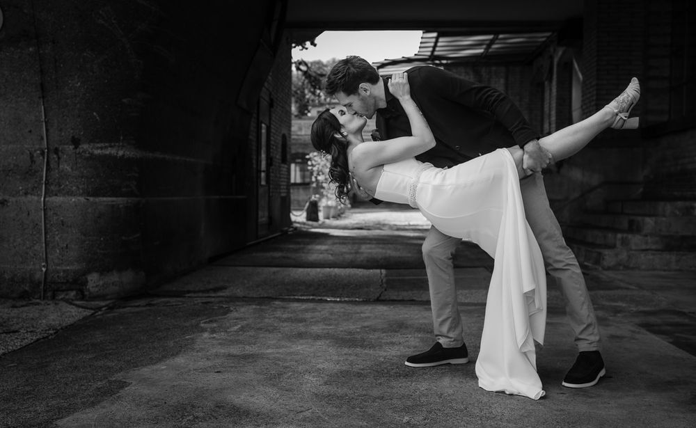 Black and white photo of groom dramatically dipping bride in romantic urban setting.