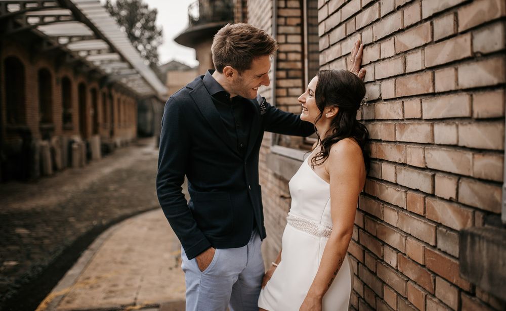 Couple sharing romantic moment leaning against brick wall in urban alley setting.