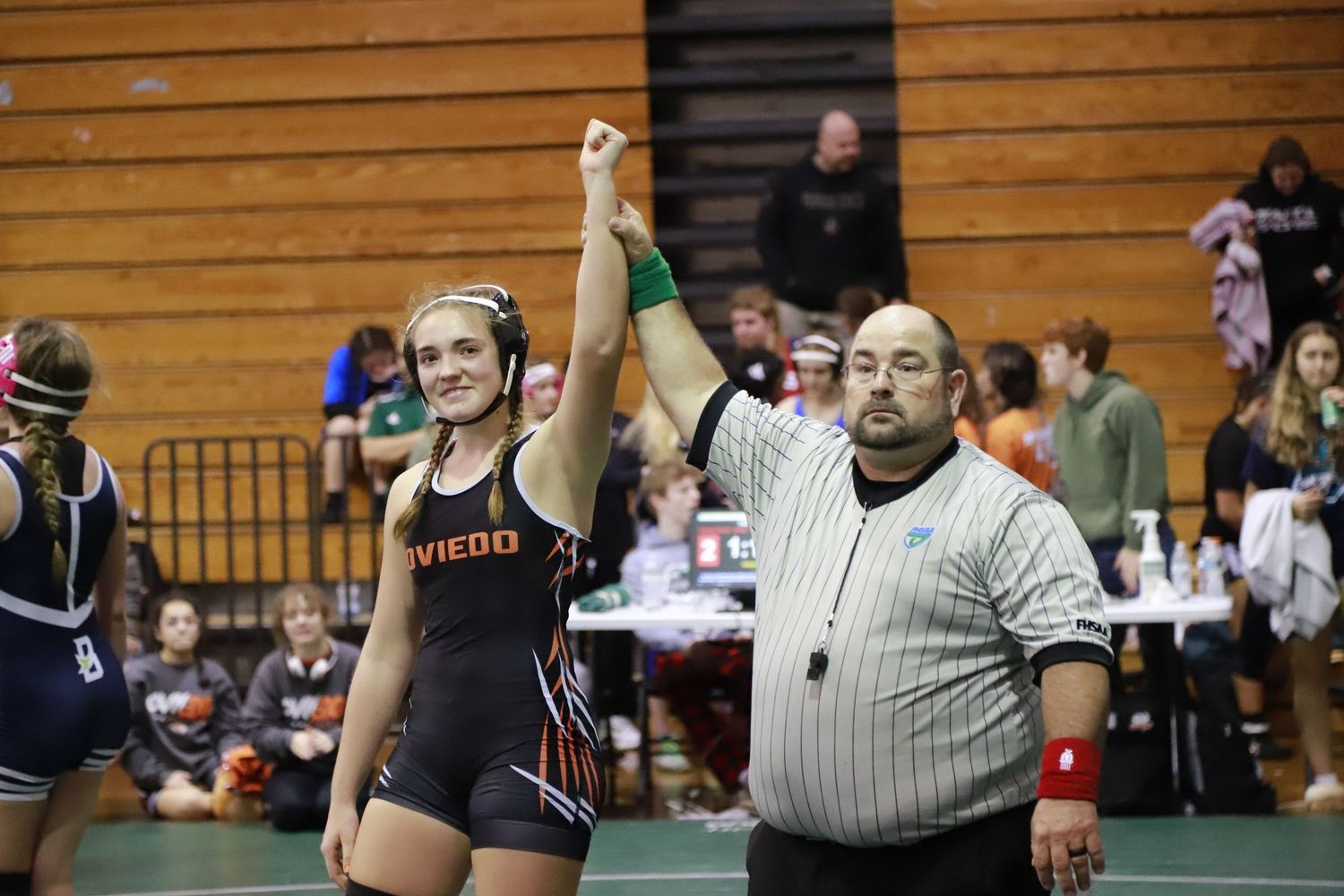 High school wrestler celebrates victory with raised arm as referee signals the win. Oviedo, Florida