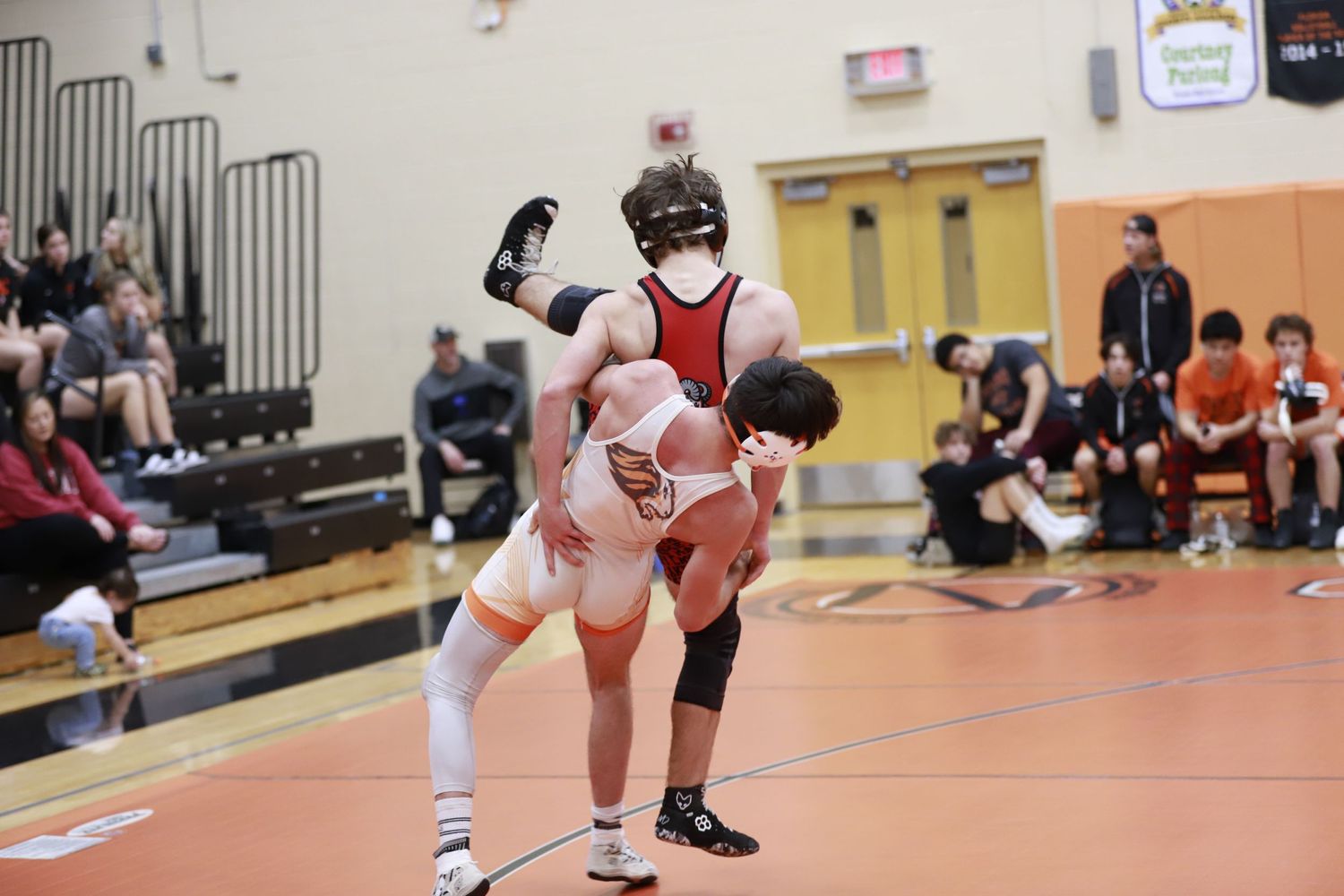 Two wrestlers grappling during a competitive match on red and white mat. Oviedo, Florida
