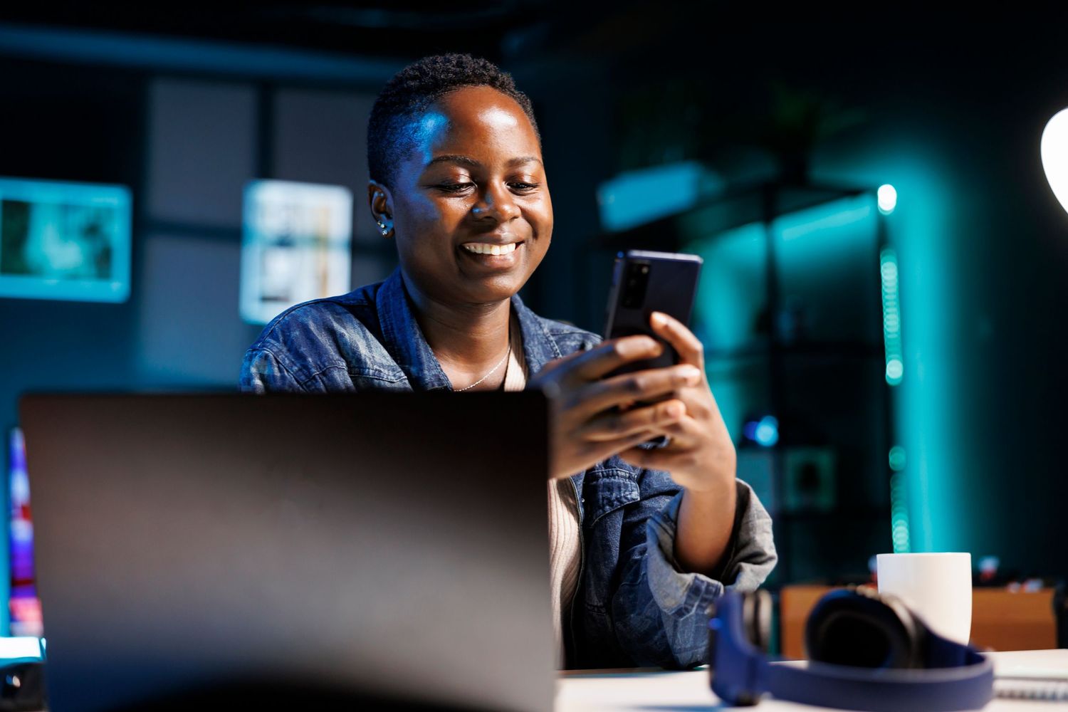 Cheerful female college student using mobile device to engage with friends on social media platforms. African american l