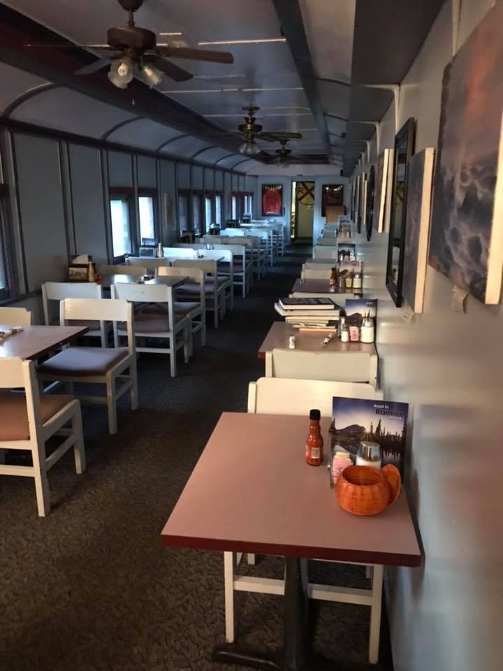 Interior of train car restaurant with booths and tables arranged in long rows.