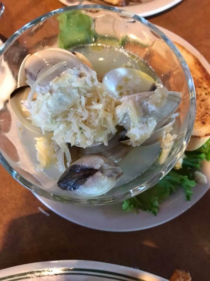 Fresh oysters on the half shell served in a glass dish with garnish.