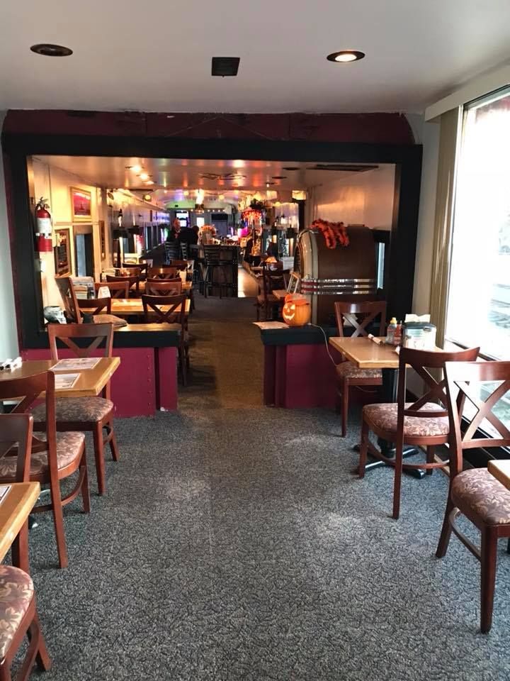 Interior view of a restaurant dining room with wooden chairs and burgundy decor.