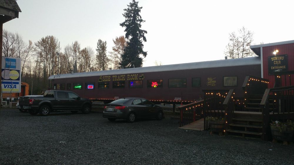 Long restaurant building with parked cars and holiday lights in evening light.