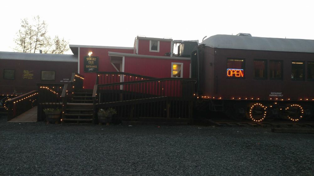 Vintage red train car decorated with festive Christmas lights at dusk.