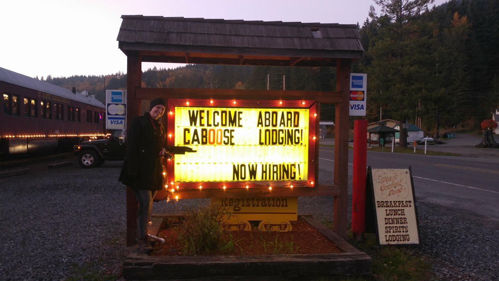 Illuminated welcome sign with string lights at entrance of outdoor venue.