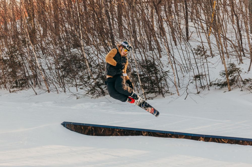 A snowboarder performs a jump sequence on snowy terrain, captured in multiple action shots showing the progression of the trick.