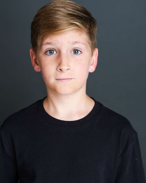 Studio portrait of a young person wearing a black shirt against a dark gray background.