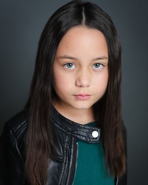 Close-up studio portraits of a young person with long dark hair wearing a leather jacket and green top against dark background.