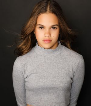 Professional portrait in grey turtleneck against dark backdrop.