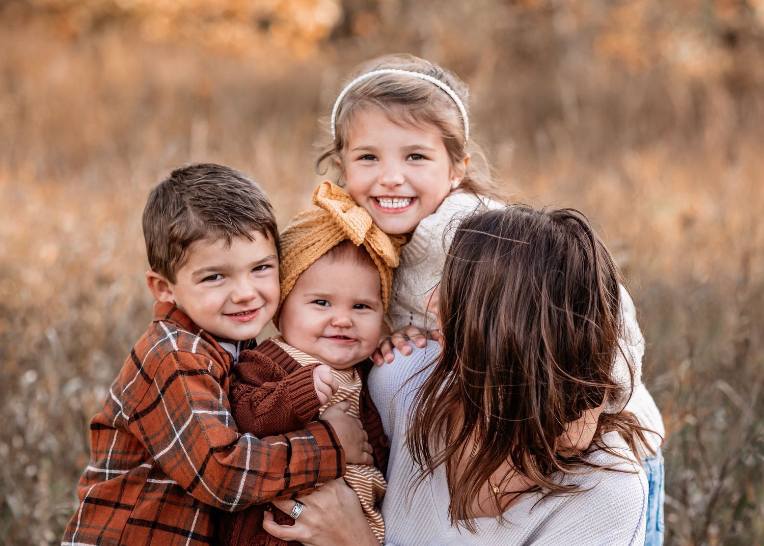 Family portrait captured in warm autumn light with a soft brown background.
