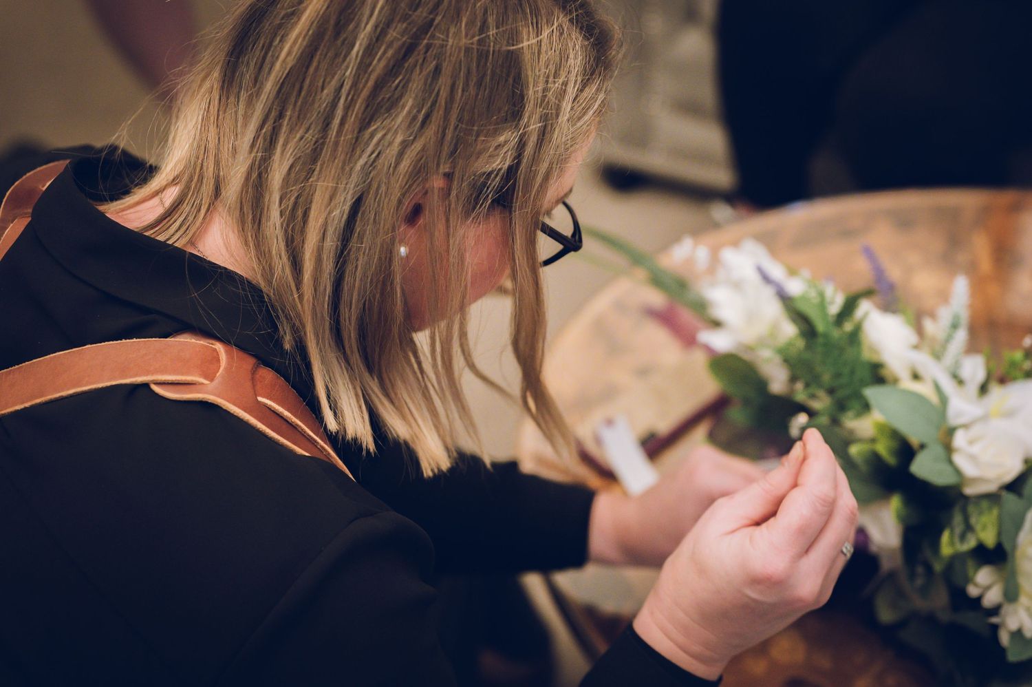 Professional florist arranges delicate white wedding flowers.