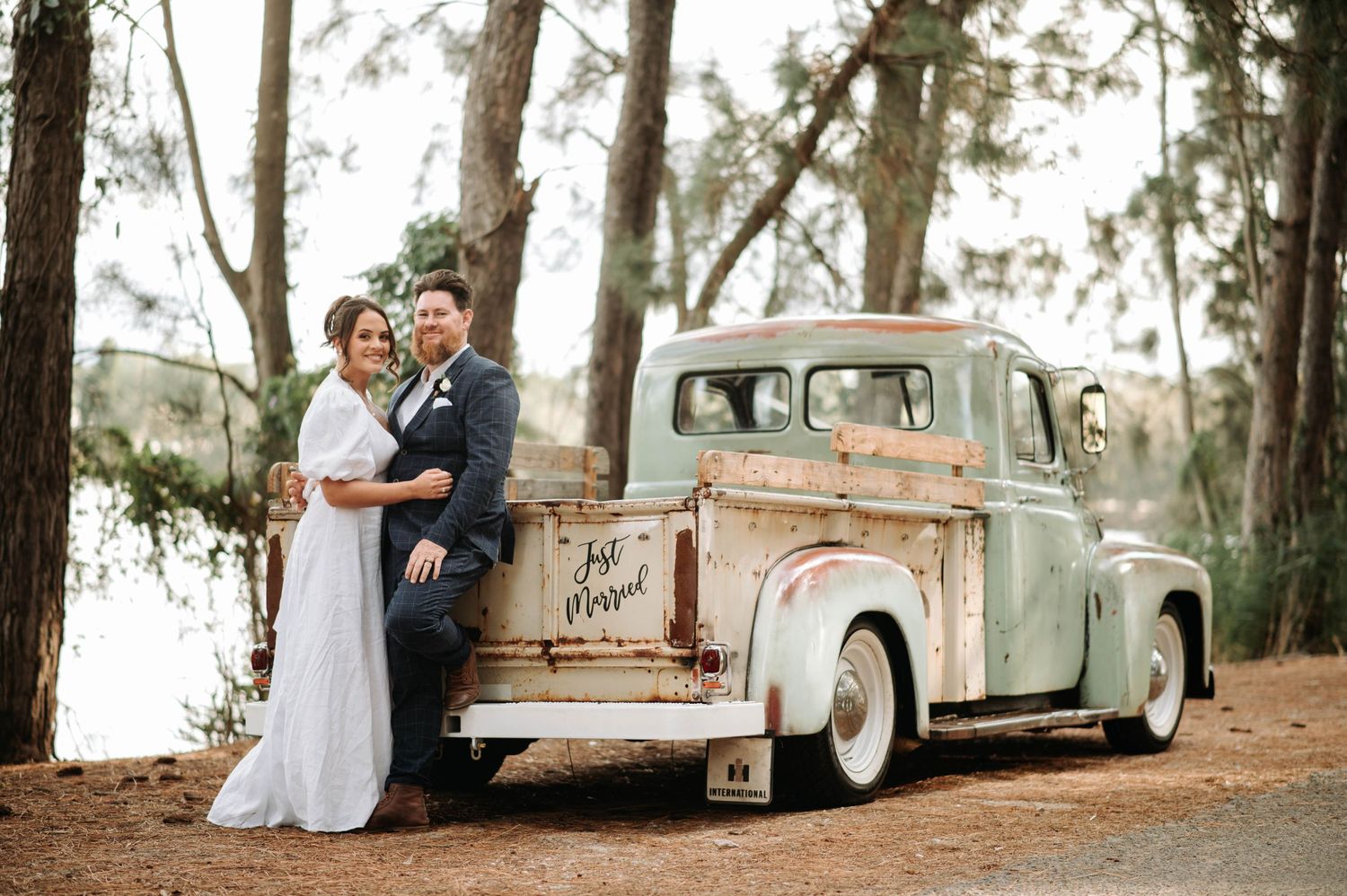 A vintage mint pickup truck with newlyweds in a pine forest setting.