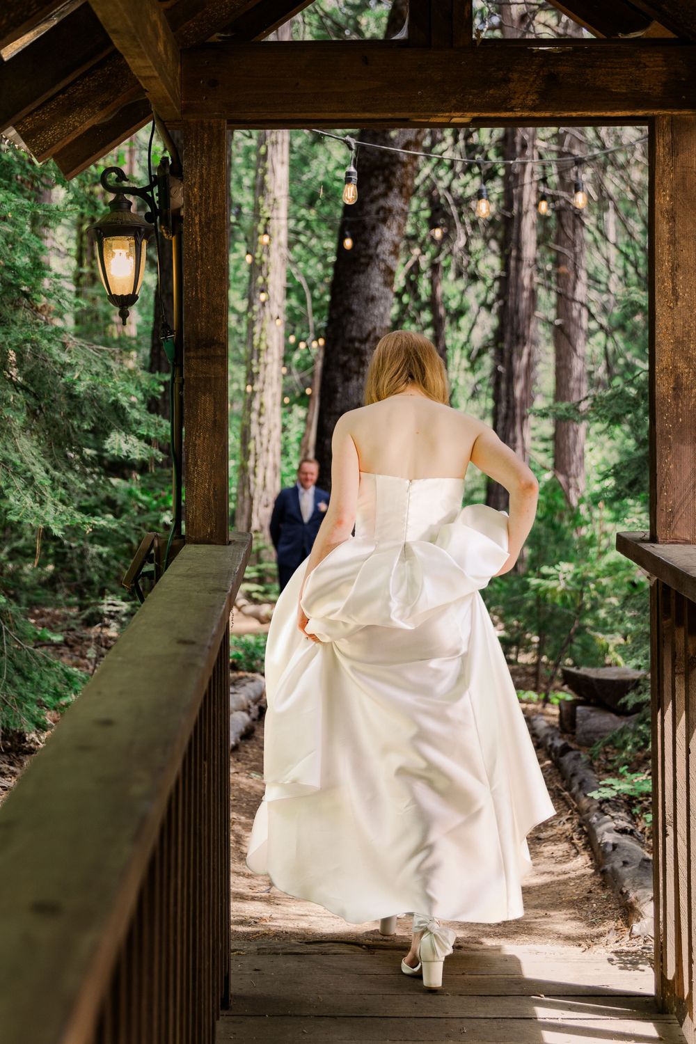 A bride's flowing white dress catches movement in a rustic wooden gazebo surrounded by forest.