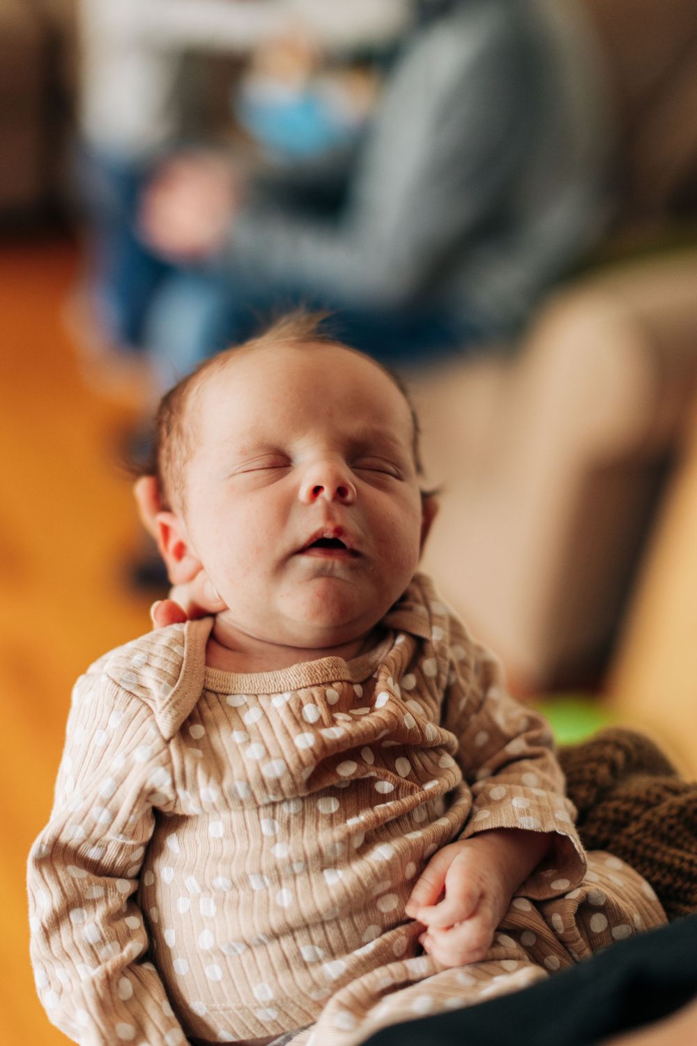 A sleeping infant wearing a striped onesie rests peacefully.