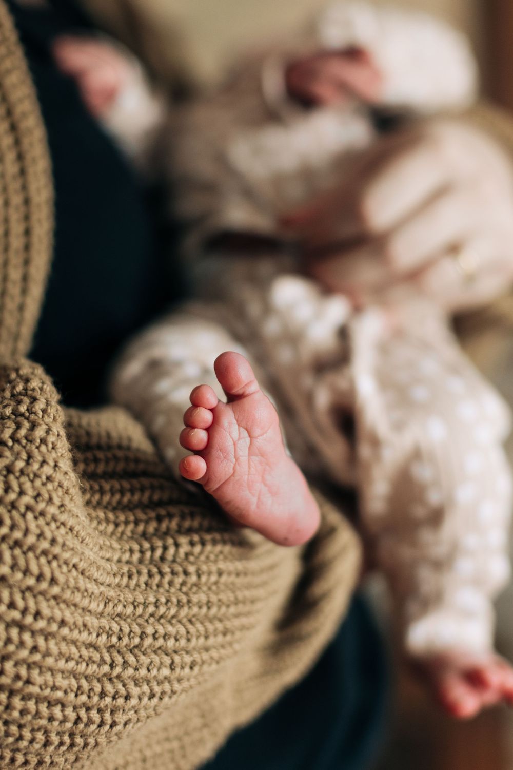 Close-up of tiny baby feet against a cozy knit sweater background.