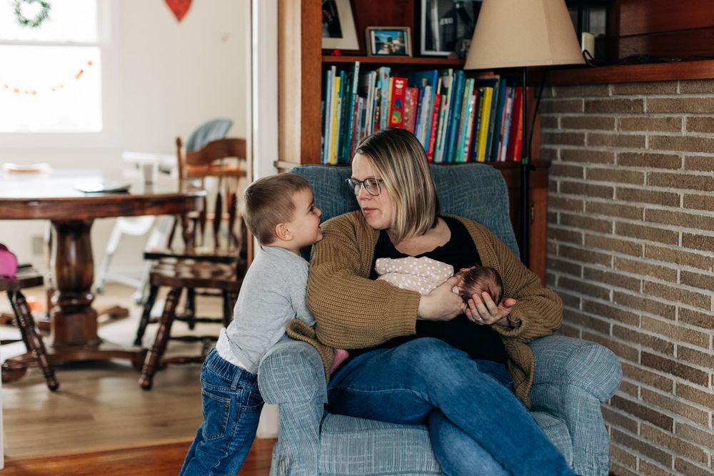 A candid moment of connection and snuggles in a cozy reading nook with bookshelves in the background.