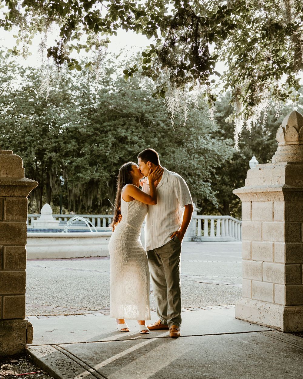 Romantic moment under stone archway at sunset.