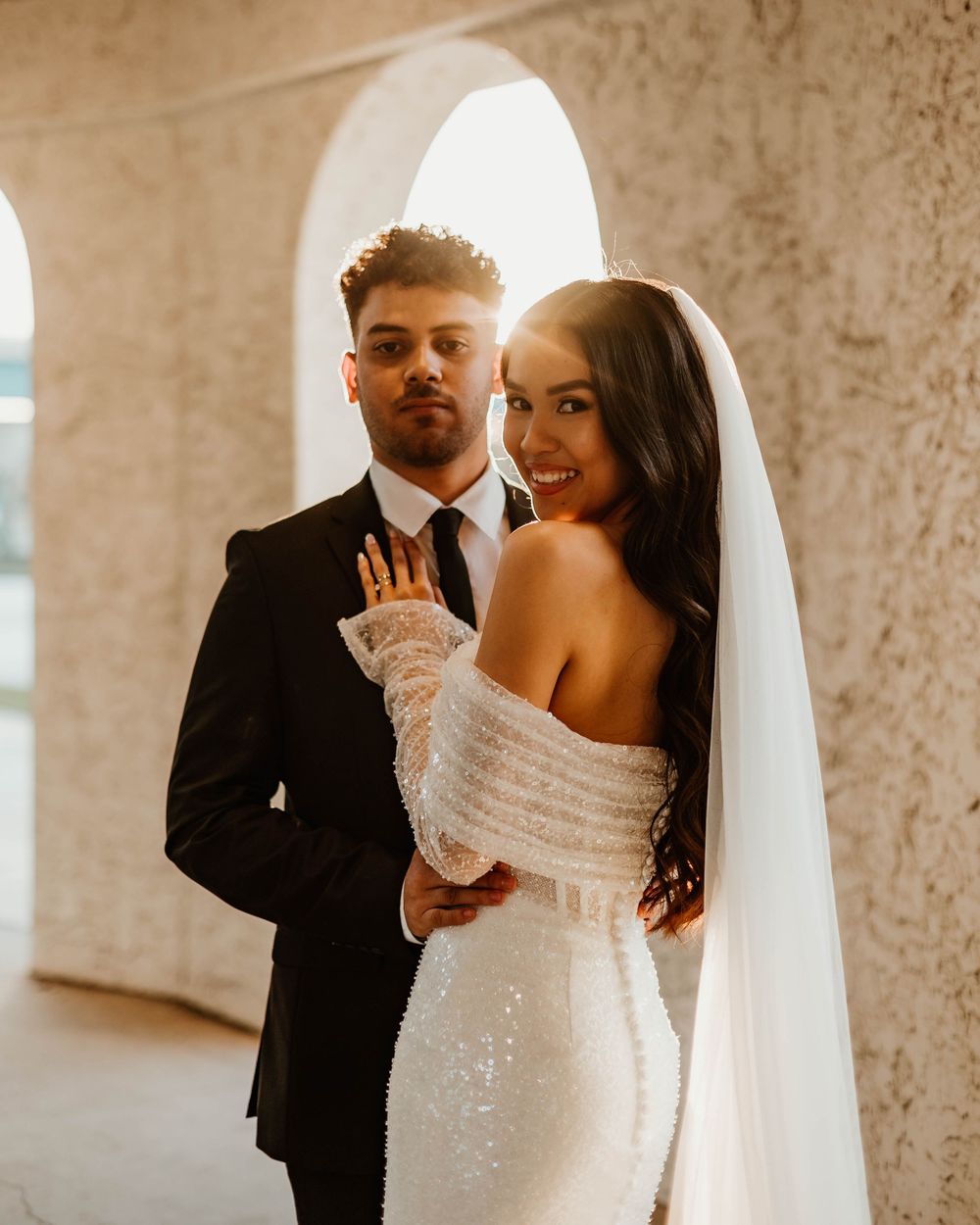 Elegant couple sharing tender moment under arched passageway.