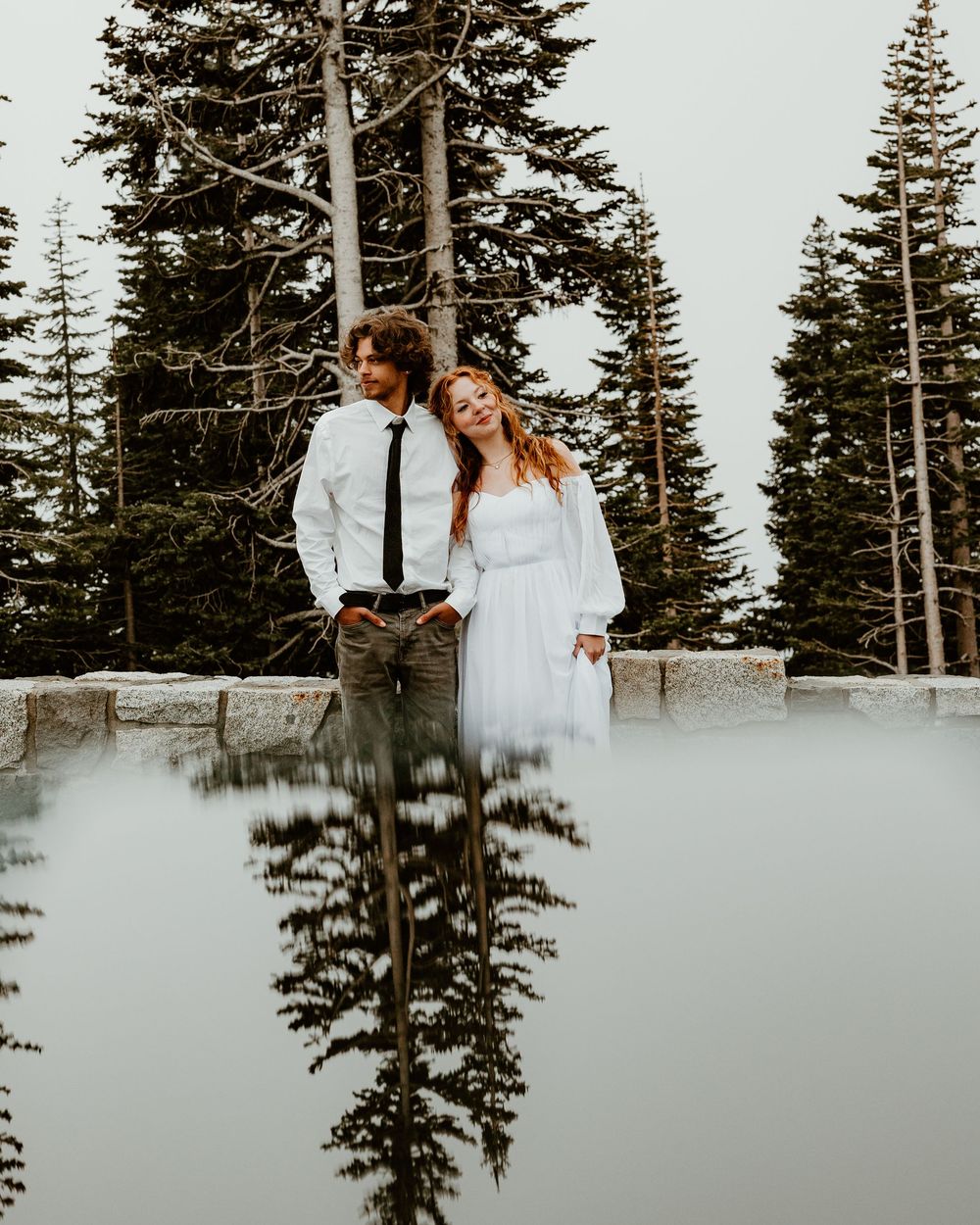 Snowy winter photoshoot with evergreen trees and mountain backdrop.