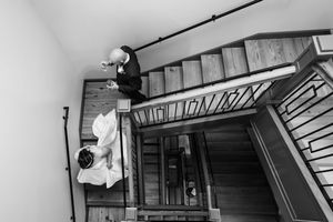 Black and white aerial view of bride and groom on wooden staircase at wedding venue.