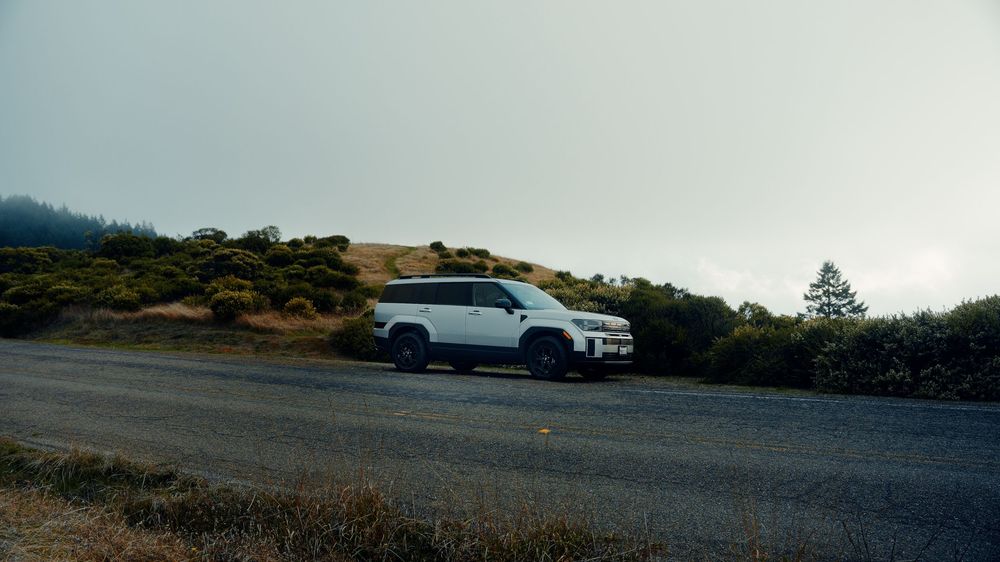 White SUV parked on a scenic mountain overlook during overcast weather.