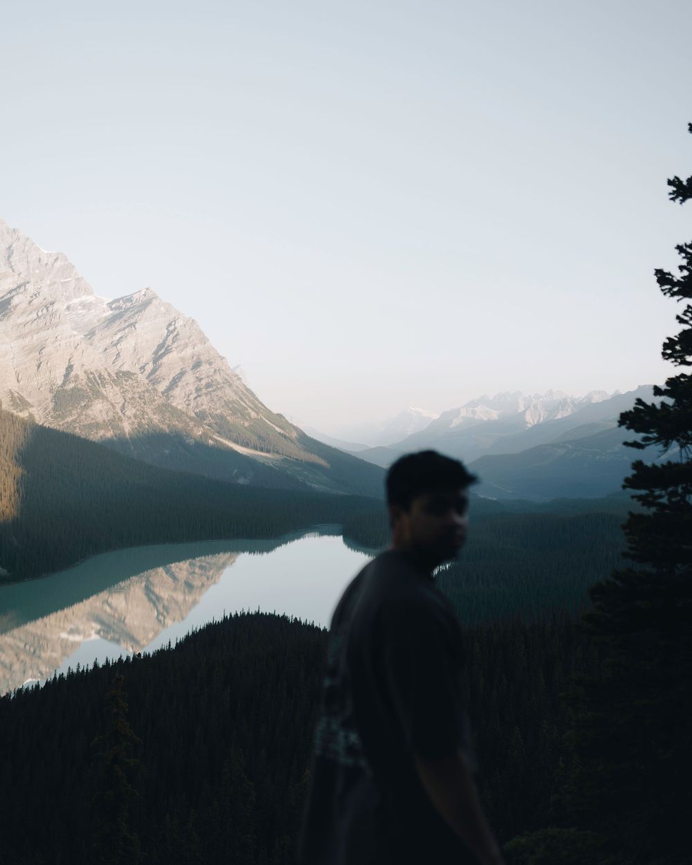 Silhouette against stunning mountain lake vista with peaks reflecting in calm waters.