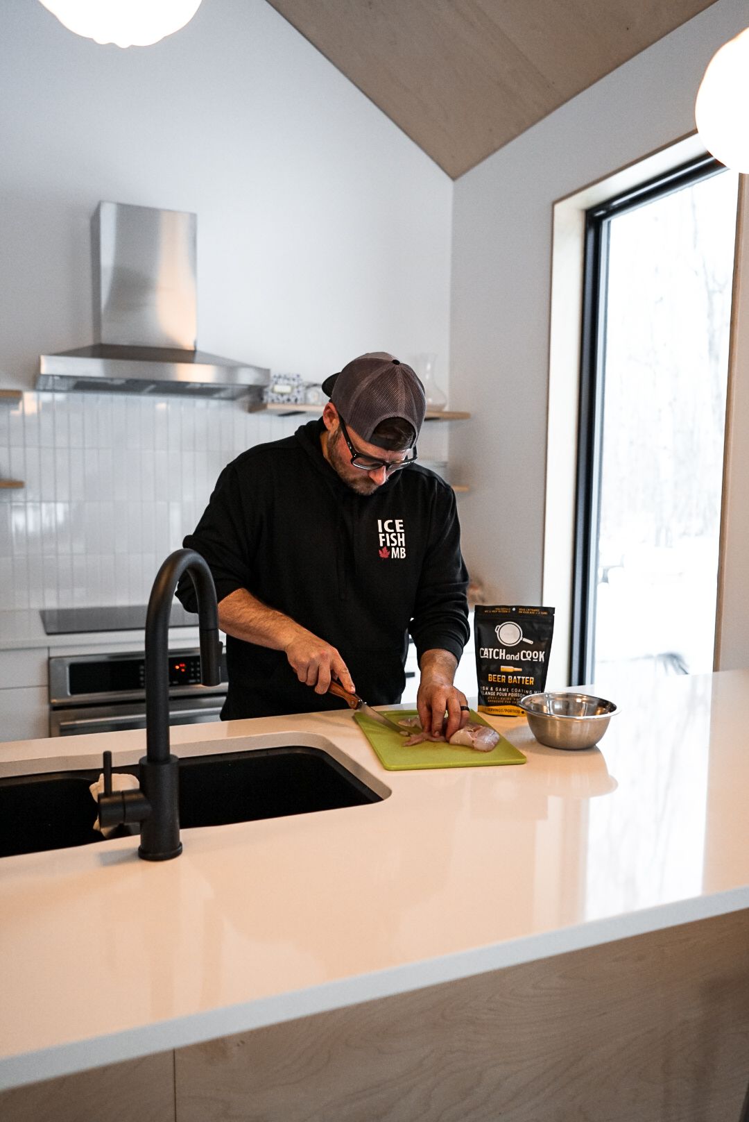 Person preparing food in a modern white kitchen with stainless steel appliances.
