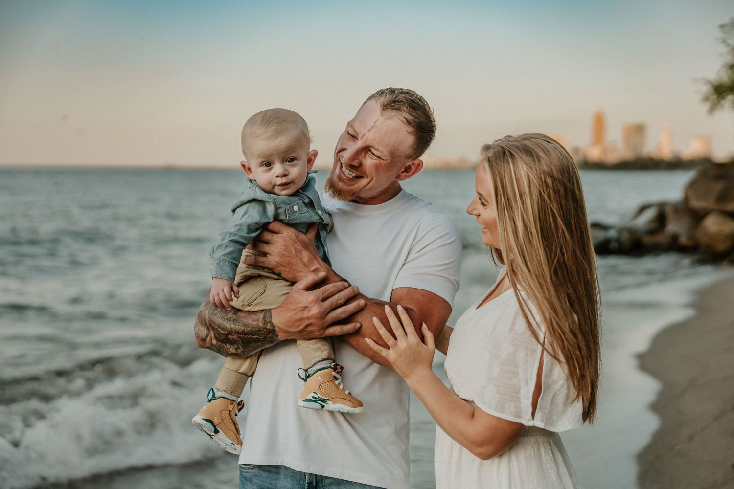 Family sharing joyful moment together on beach with city skyline in background.