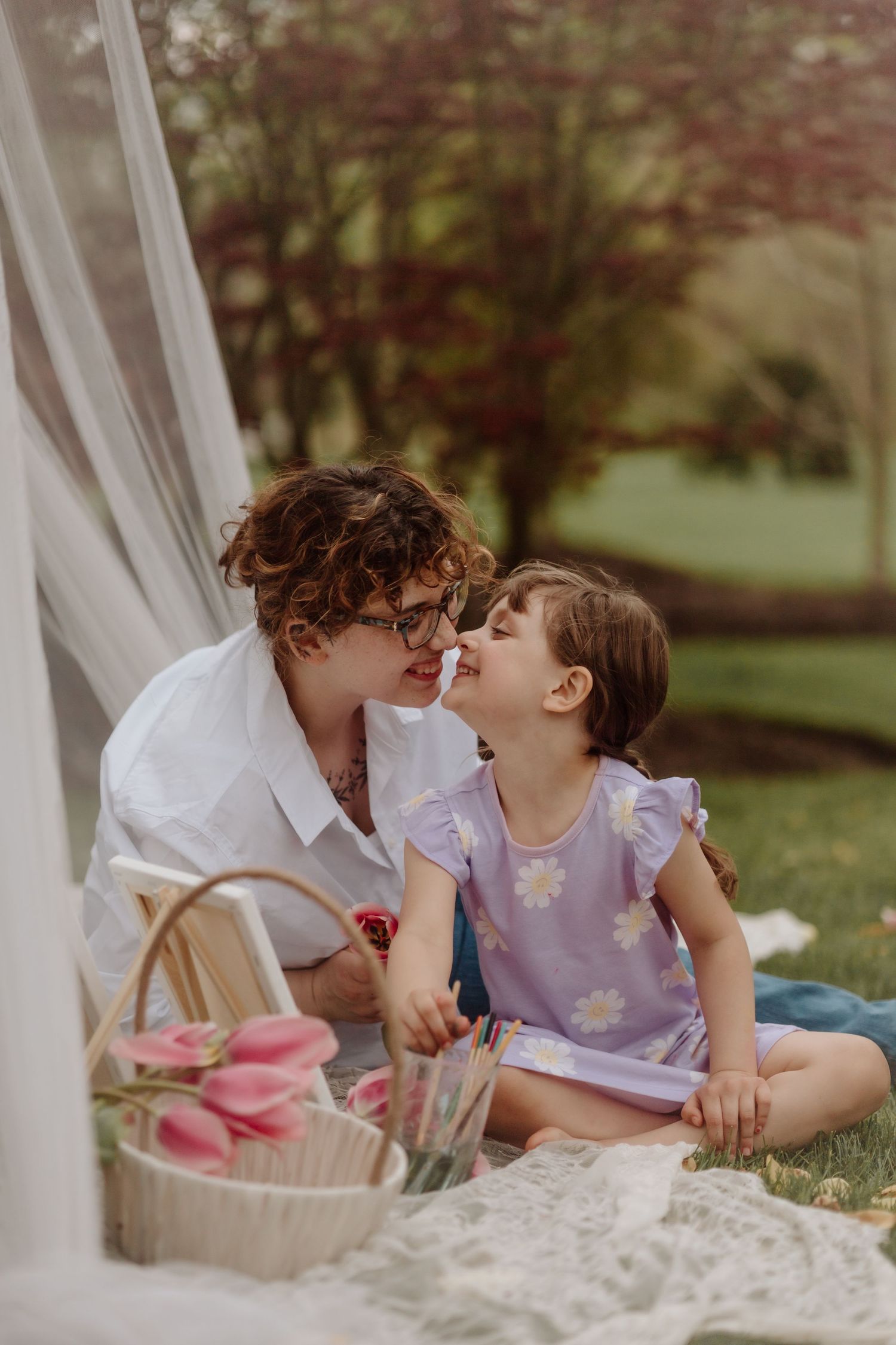 Mother and daughter share a sweet moment during an outdoor garden photoshoot with white drapes.
