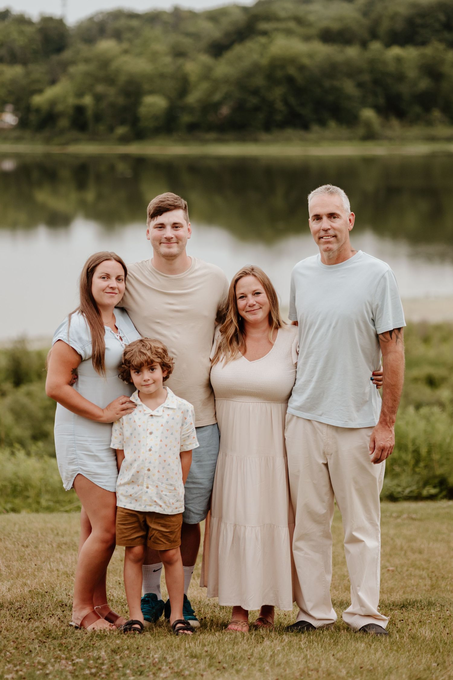 Multi-generational family portrait by a serene lake on a summer evening.