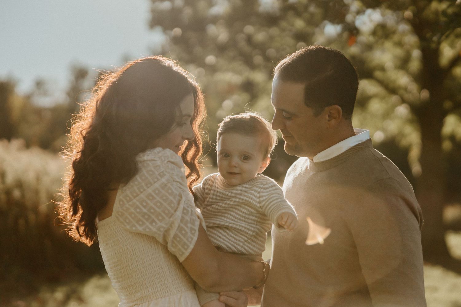 A family shares a tender moment together in warm evening sunlight against a natural backdrop.