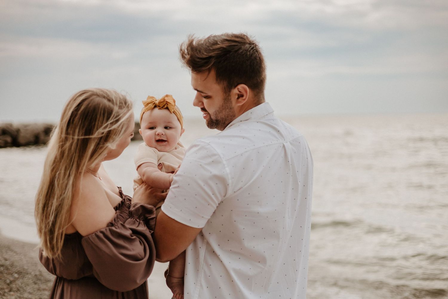 Family sharing a tender moment together on a cloudy beach day.
