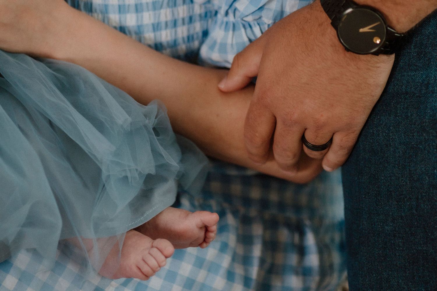 Close-up of hands holding a small foot wearing a blue tulle dress.