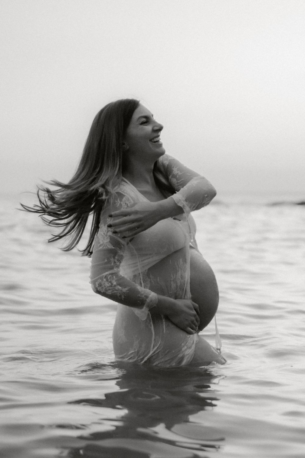 Artistic black and white maternity photo in ocean waters.