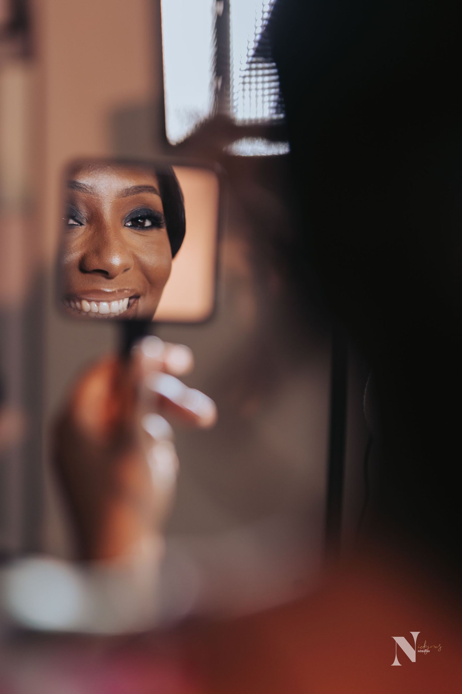 A creative mirror reflection shot captures a joyful smile during what appears to be wedding preparation.