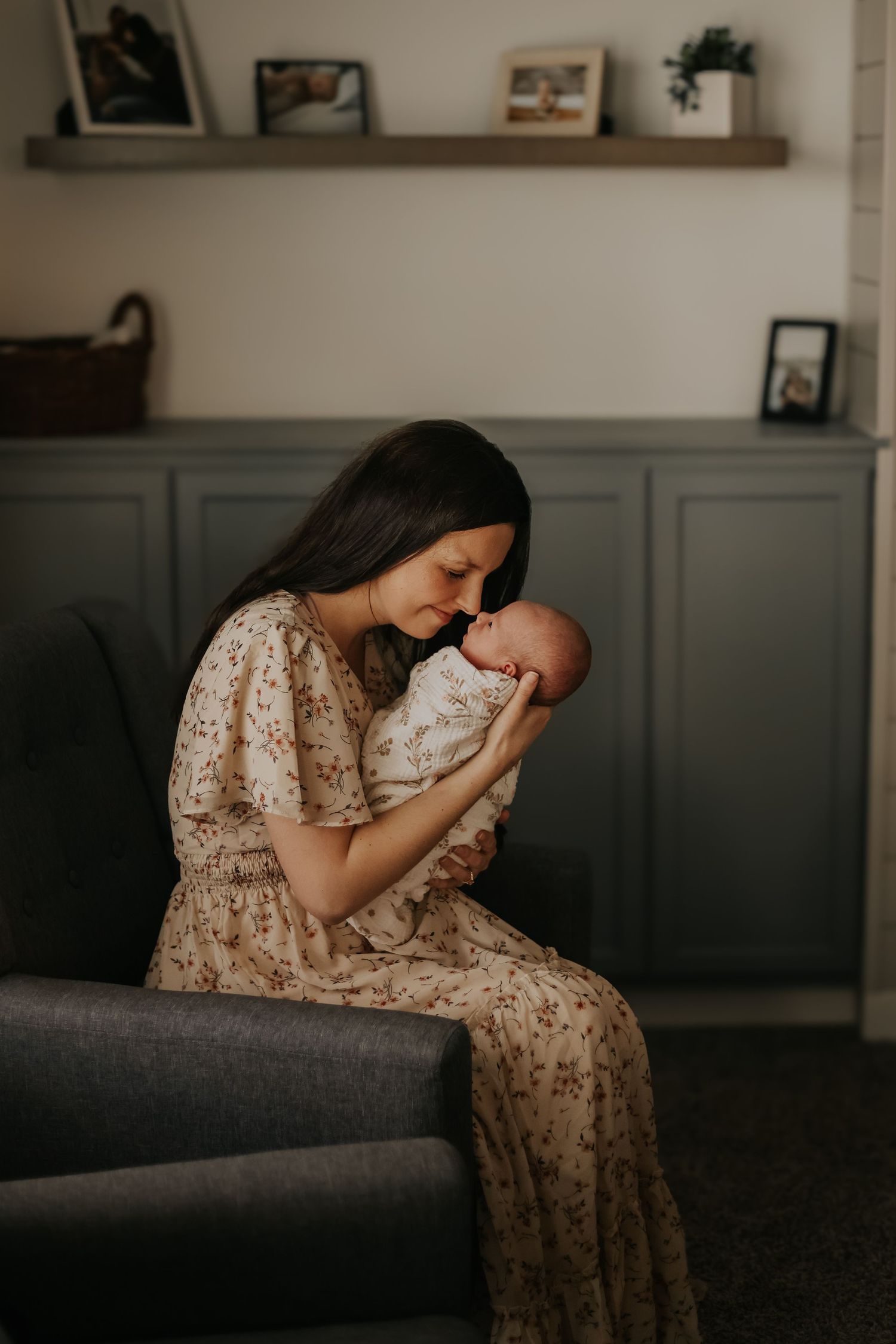 A tender moment between parent and baby on a dark gray couch with decorative shelving.