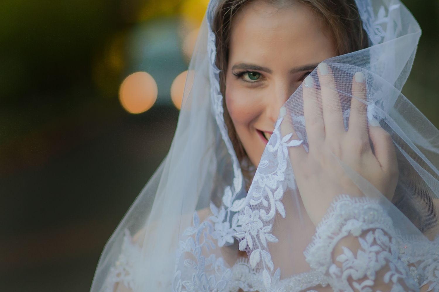 Close-up of bride wearing lace veil showing wedding ring.