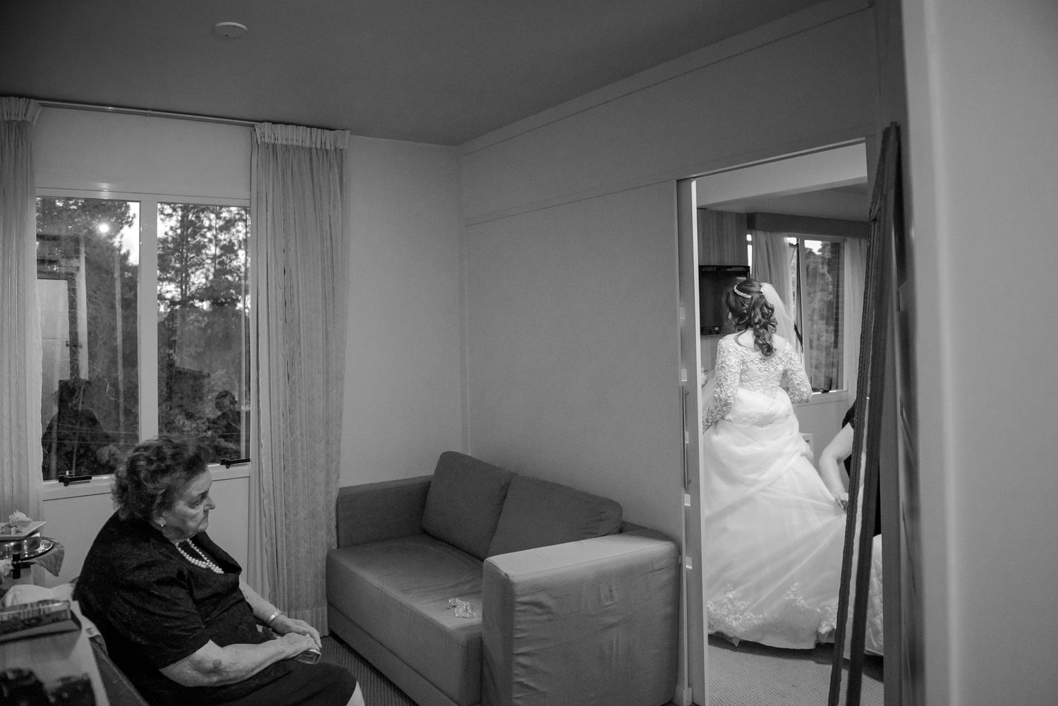 Black and white photo of wedding preparation in a bright room with window light.