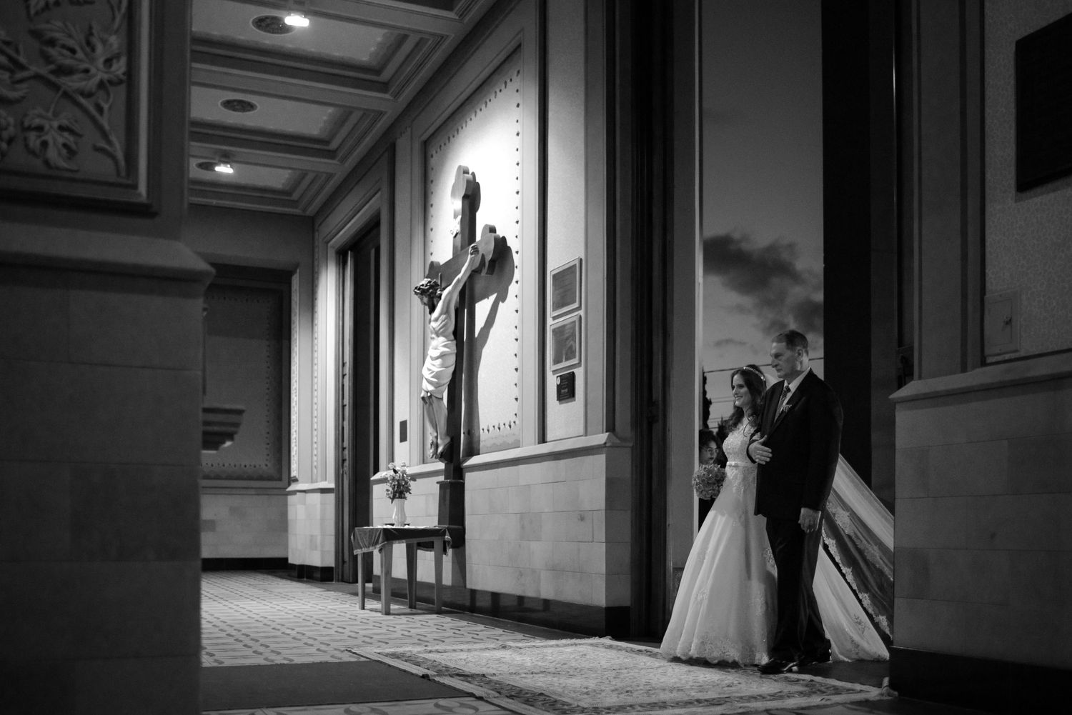Black and white artistic shot of newlyweds standing in an elegant corridor.
