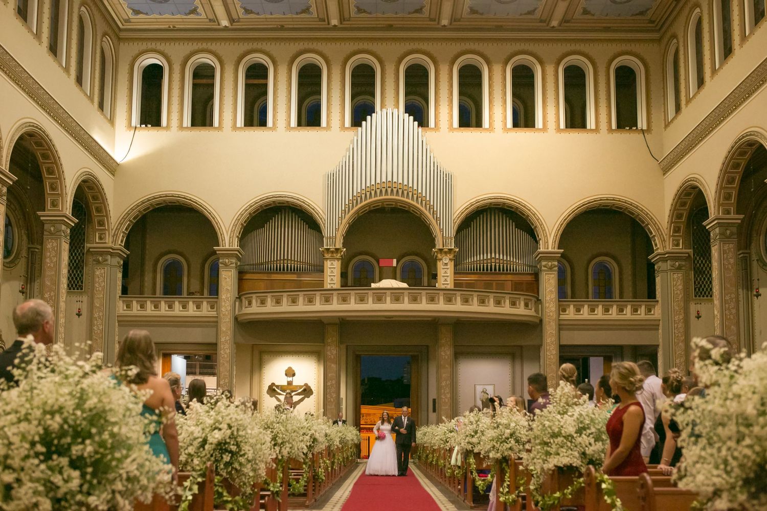 Grand church wedding ceremony with elegant floral decorations and organ pipes.