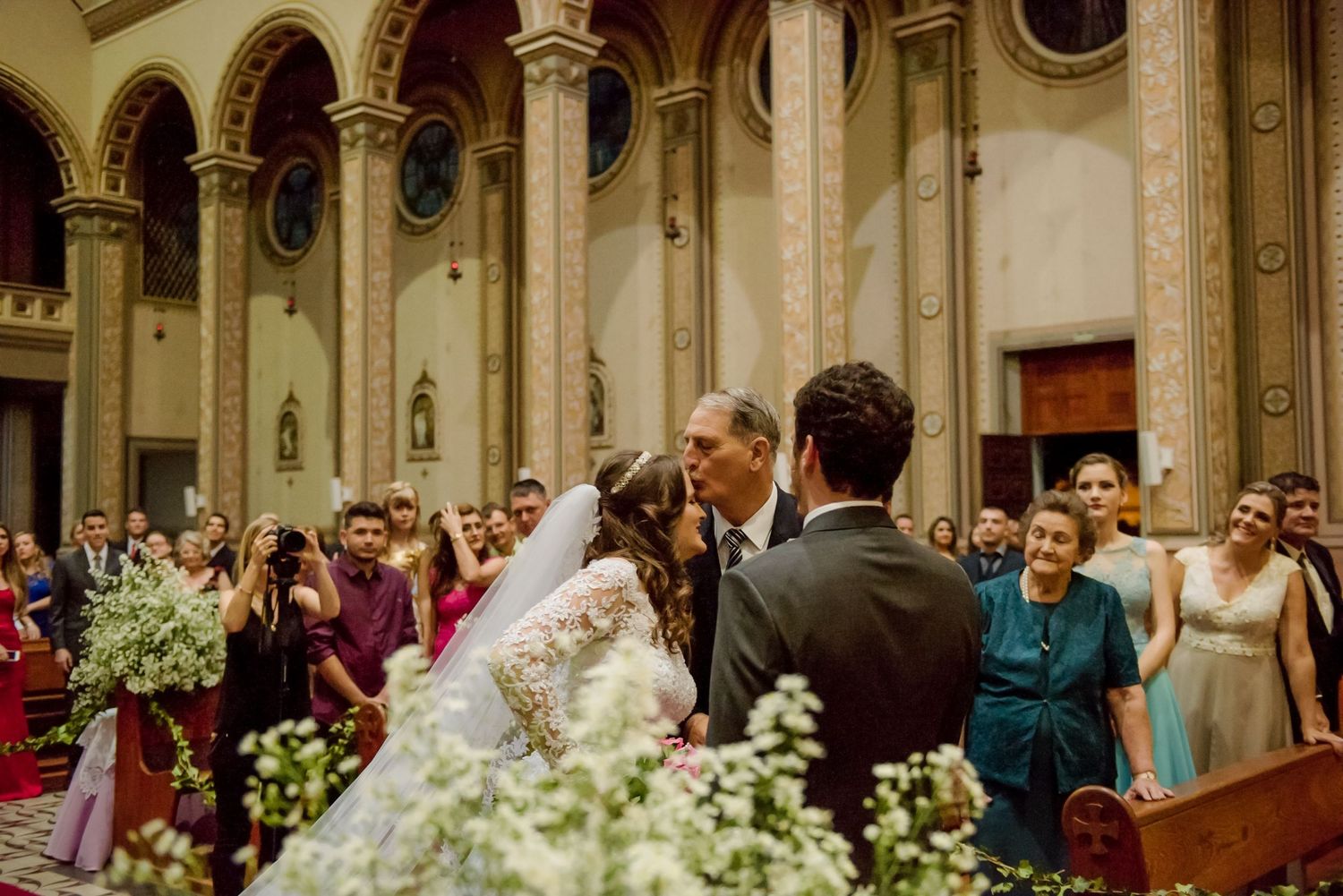 Ornate church interior filled with wedding guests and floral arrangements.