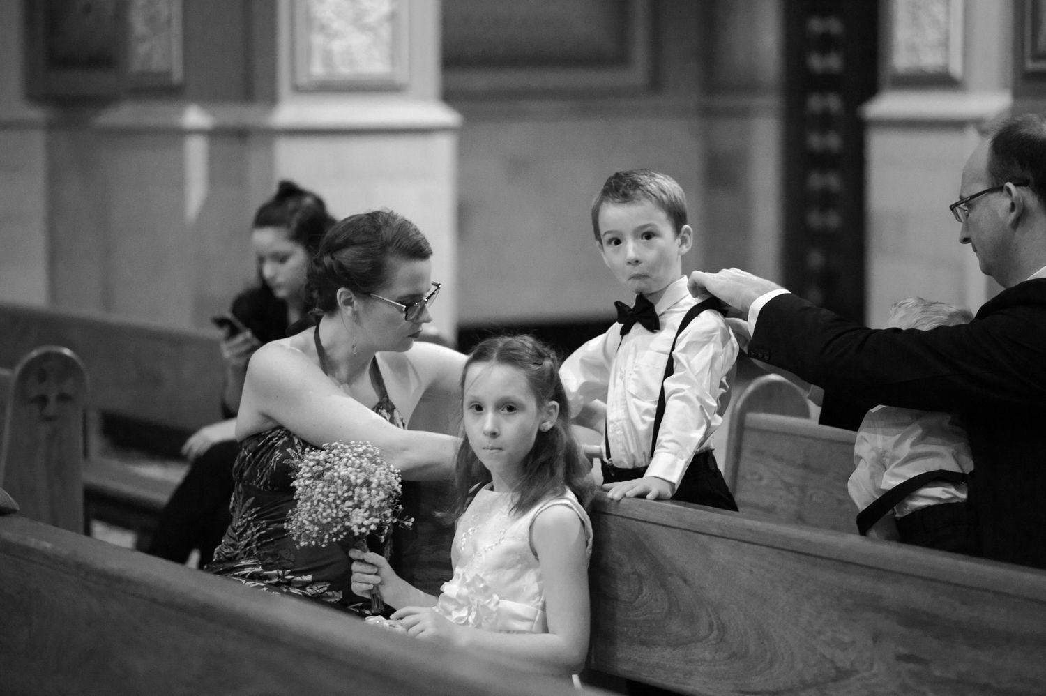 Wedding guests sit attentively in church pews during the ceremony.