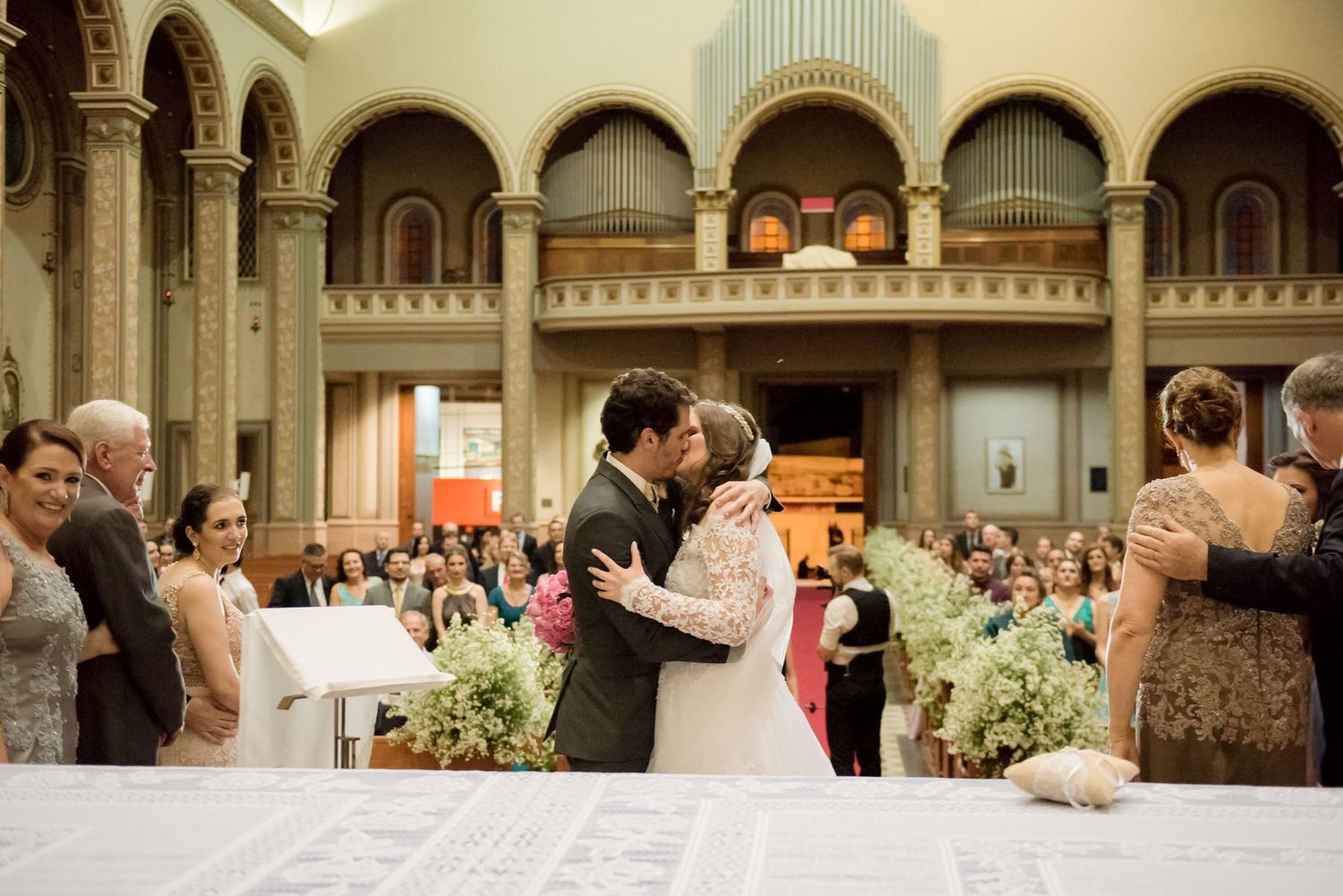 Celebratory moment during wedding ceremony in grand church setting with floral decorations.
