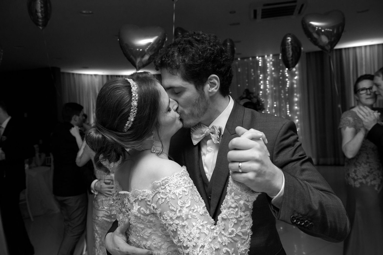 Couple shares their first dance at reception with balloons and decorations in background.