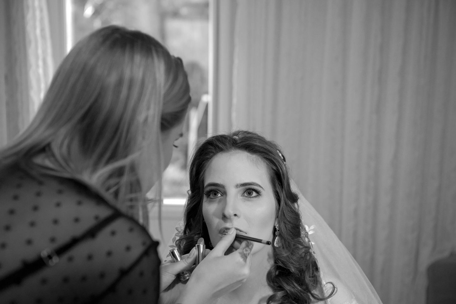 Final touches being applied during bridal makeup preparation.