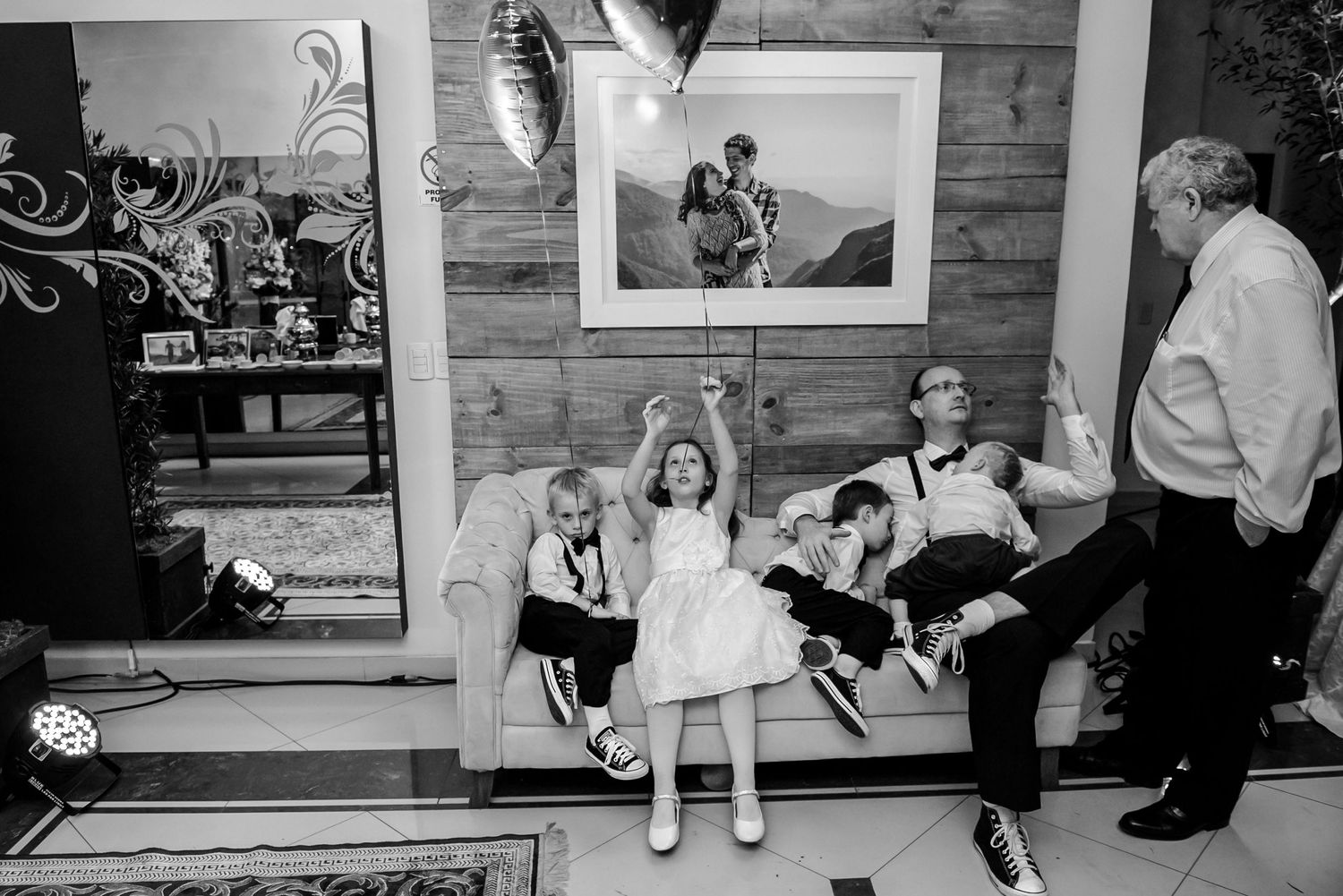 Black and white candid photo of reception guests sitting on a bench.