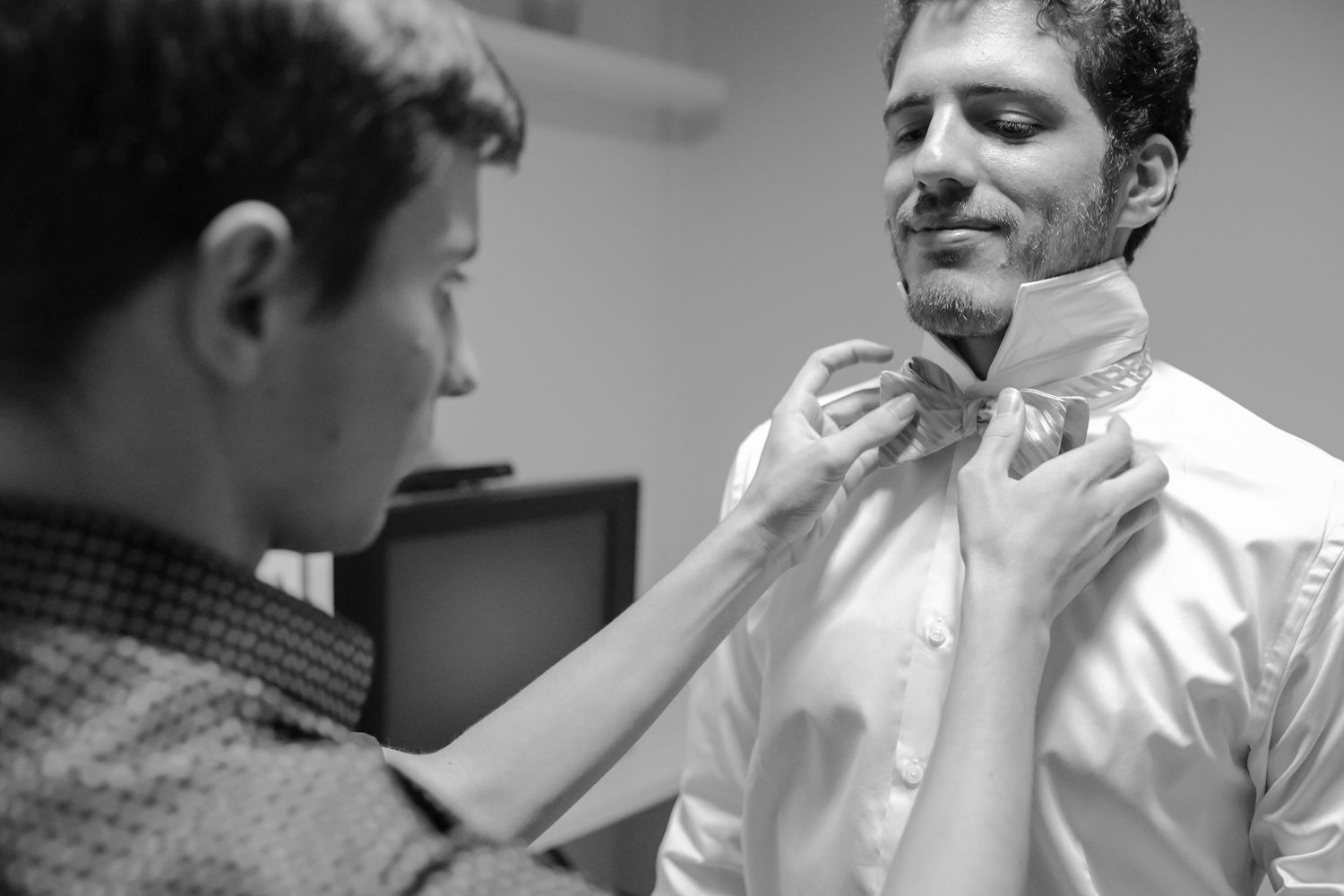 A formal bow tie being adjusted during wedding preparation.